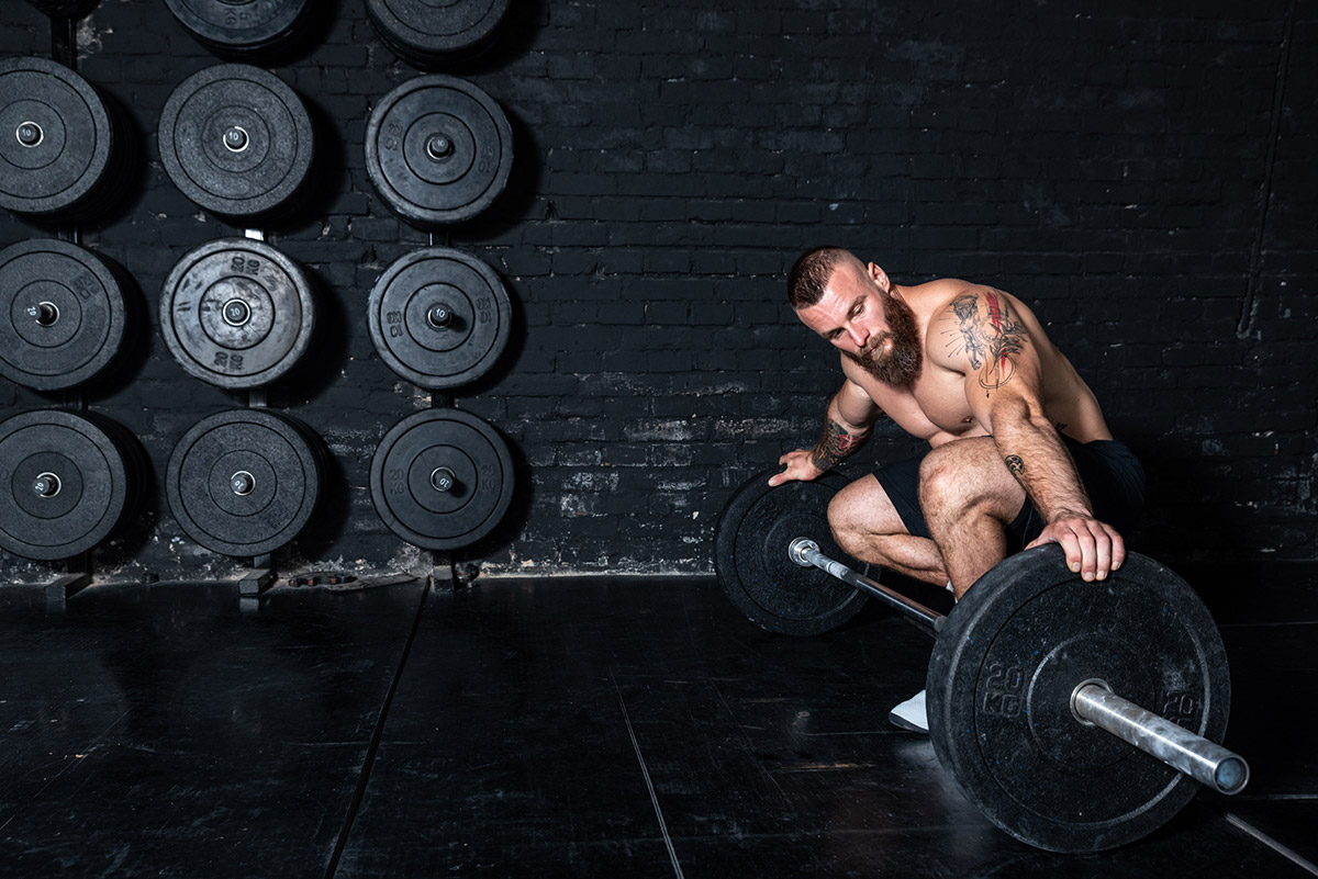 hombre cargando una barra para entrenar
