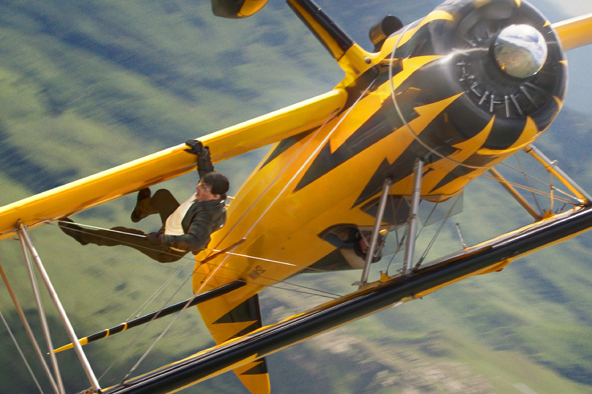 imagen de tom cruise, en su papel de ethan hunt, colgando de un avión