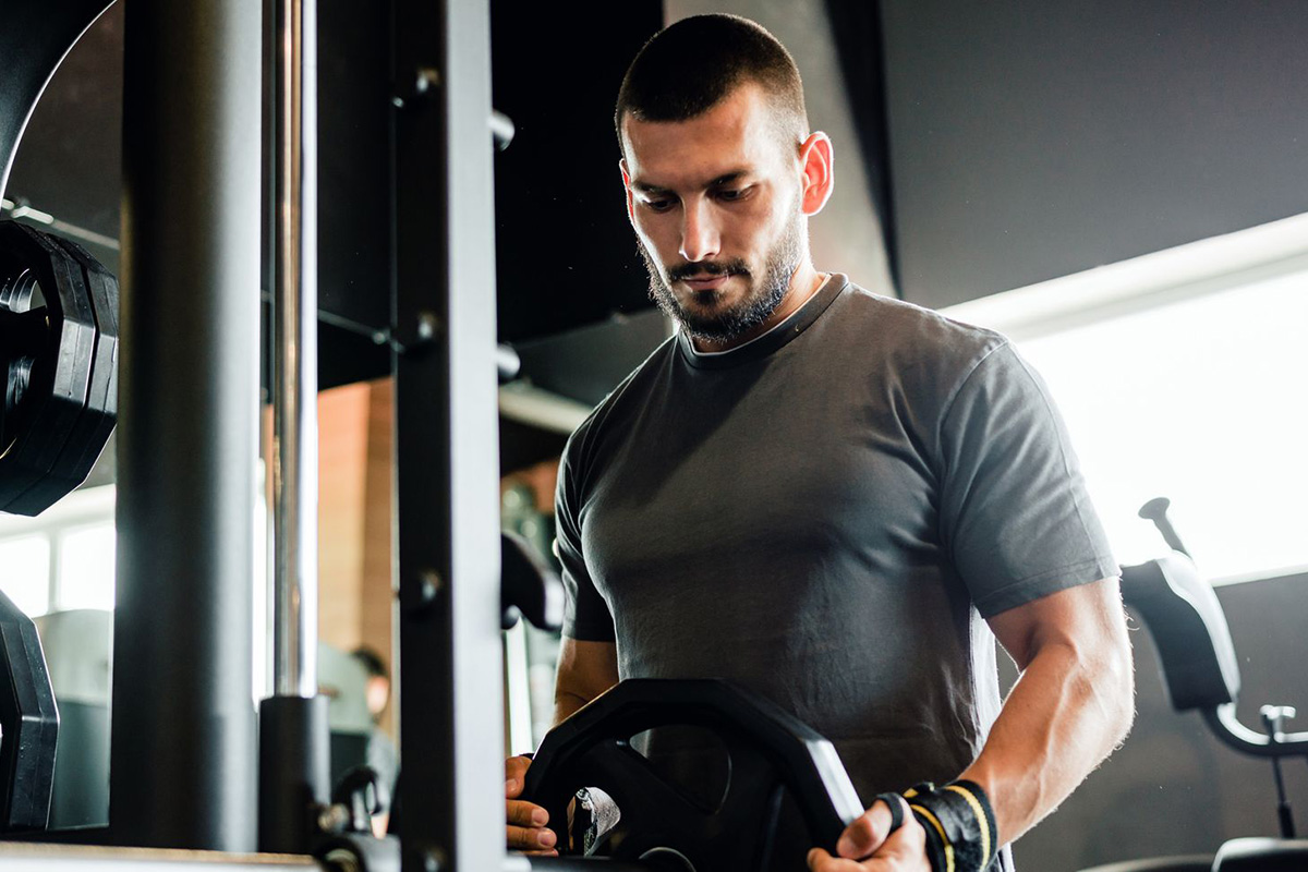 hombre colocando un disco en una máquina smith