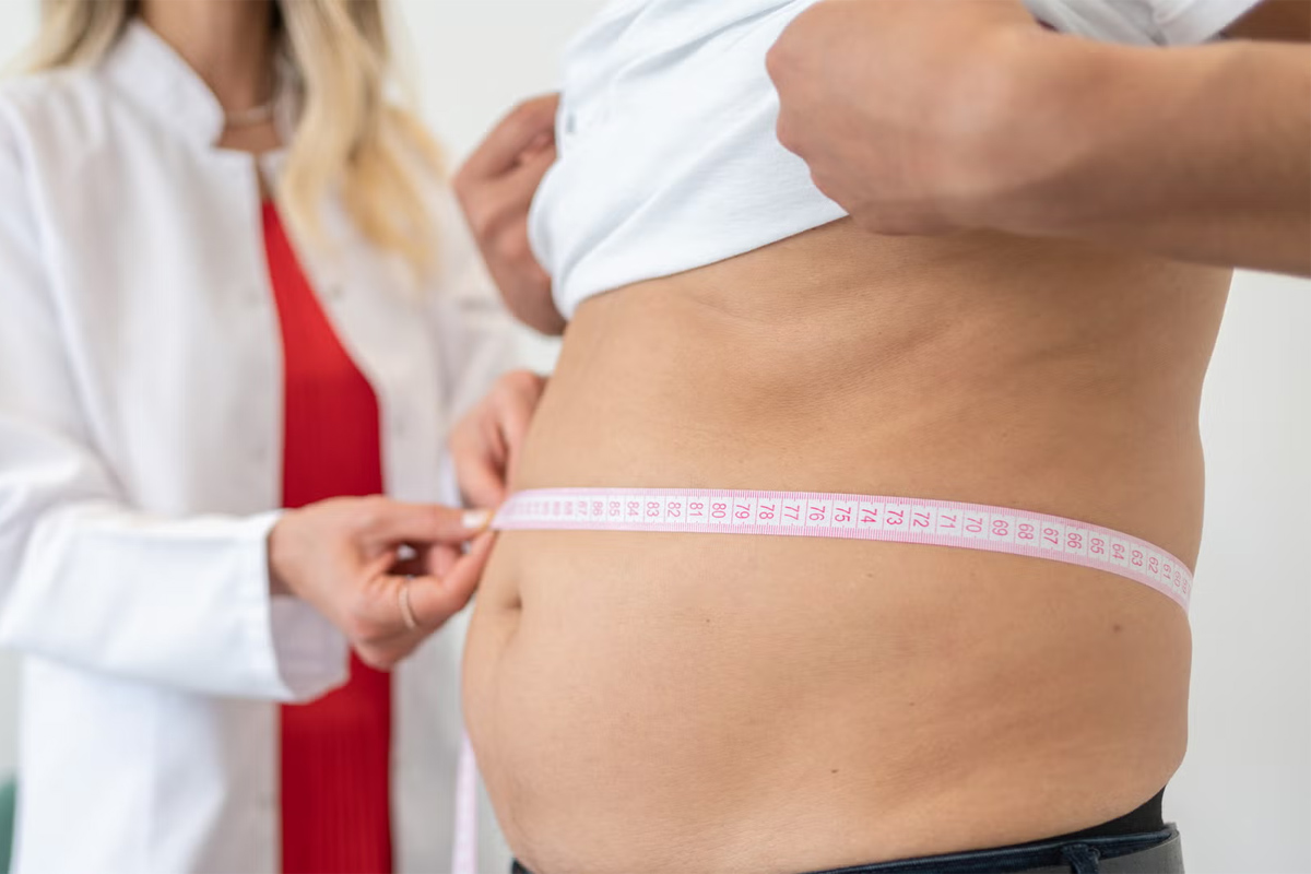 doctora midiendo el abdomen de un hombre con una cinta métrica