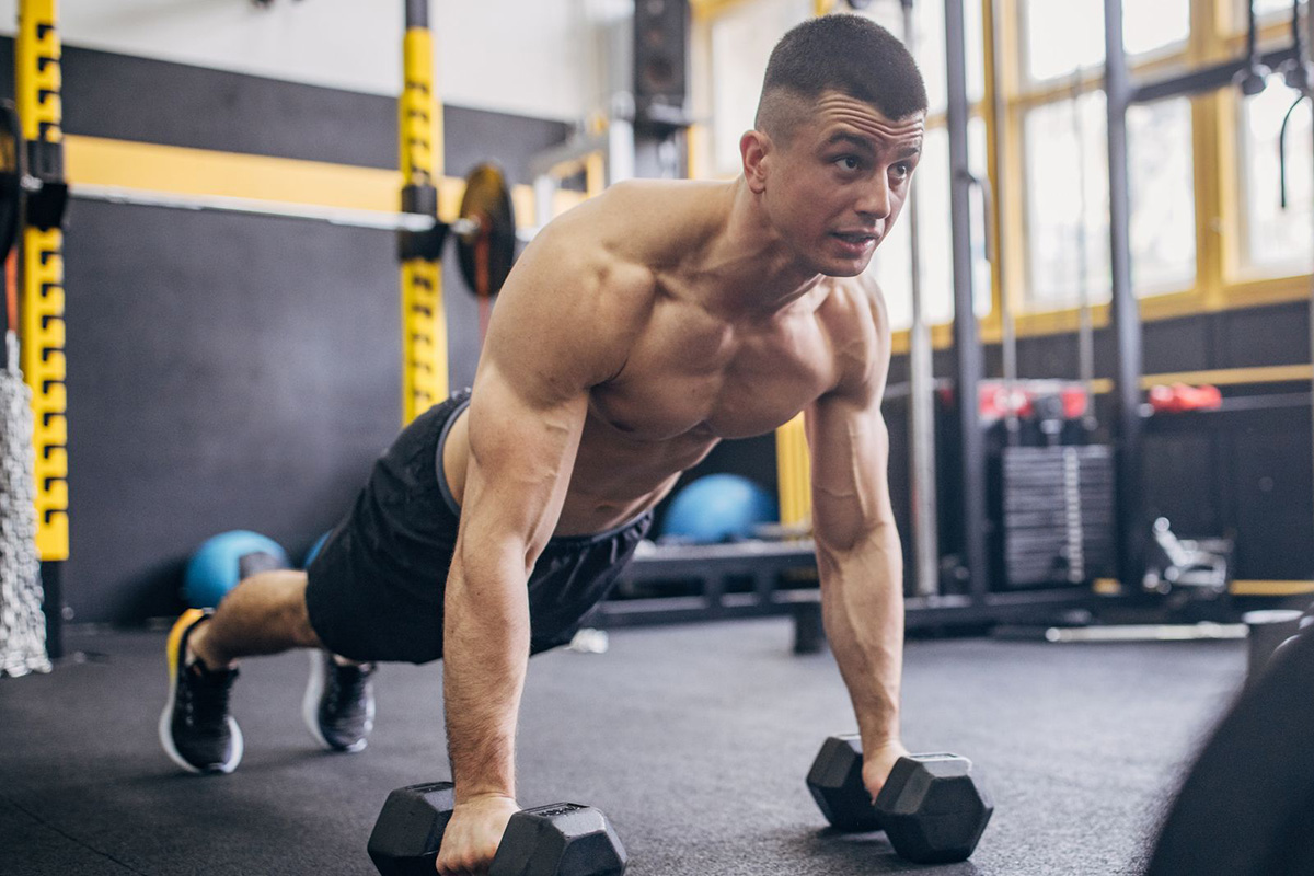 hombre haciendo lagartijas sobre mancuernas