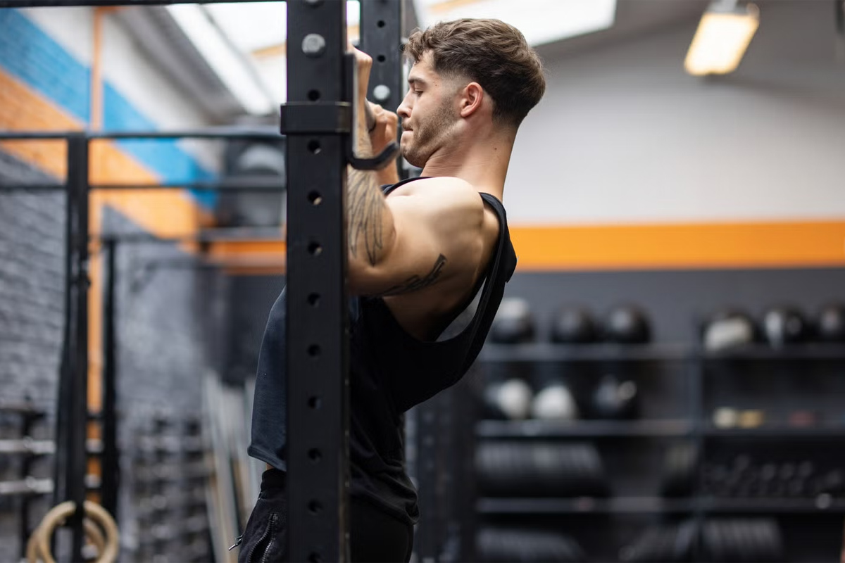 hombre haciendo dominadas en el gimnasio