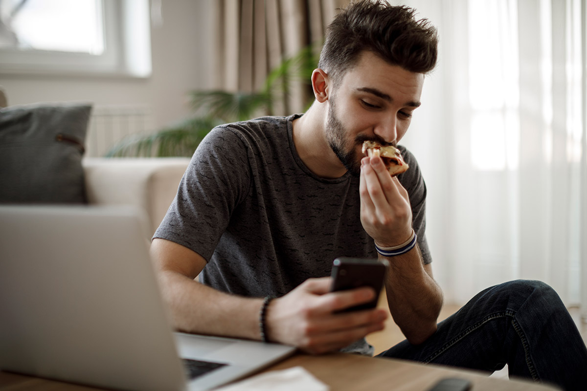 hombre comiendo mientras ve el celular