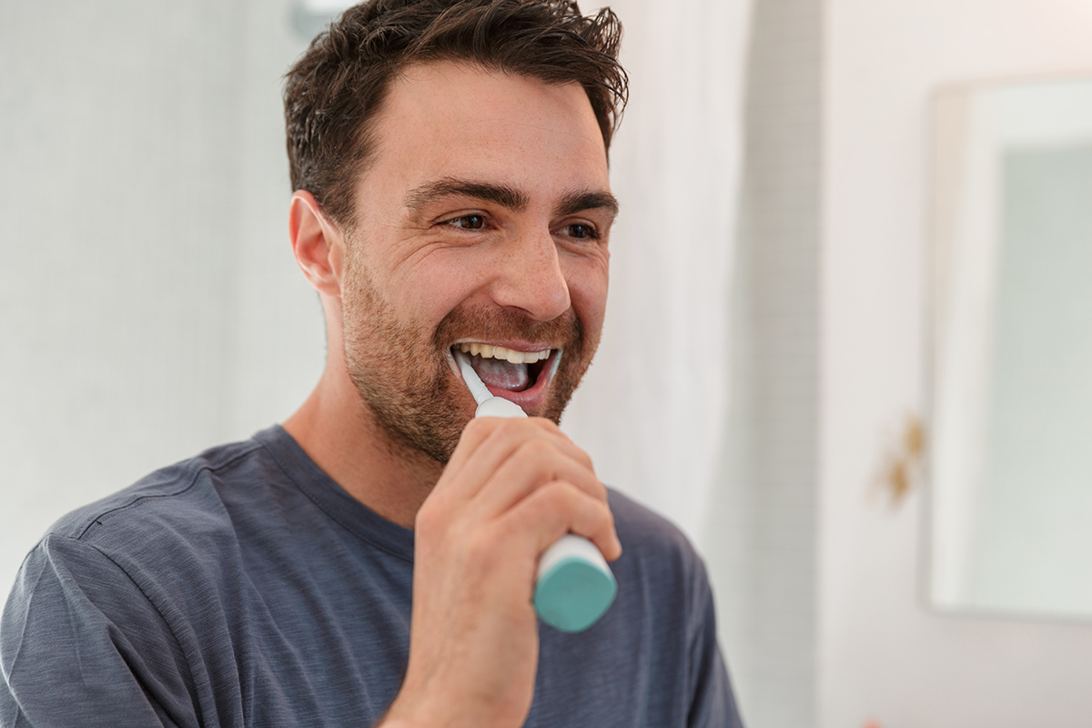 hombre cepillándose los dientes con un cepillo eléctrico