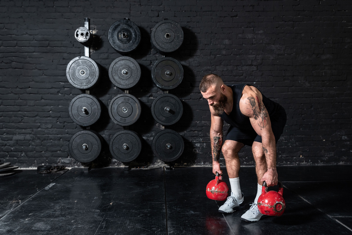 hombre cargando pesas rusas en el gimnasio