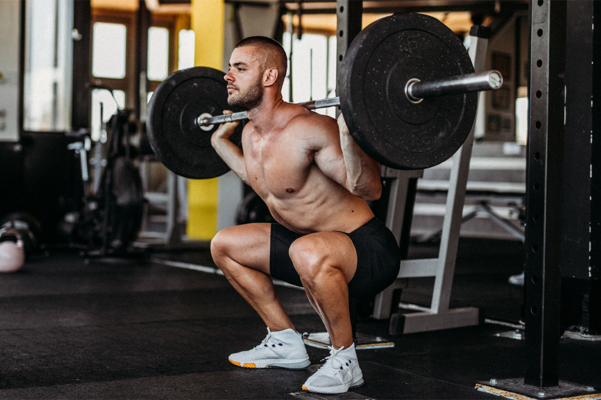 hombre haciendo sentadillas con barra tras nuca