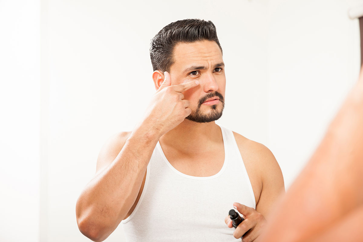 hombre aplicándose crema para los ojos